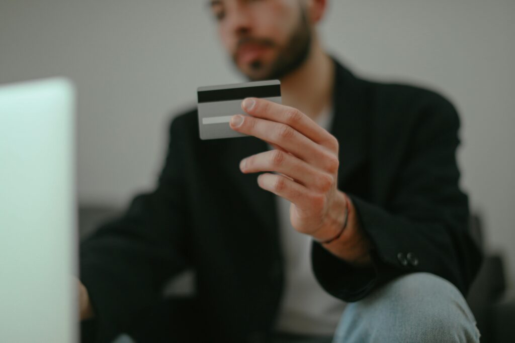 Blurred image of a man holding a credit card, emphasizing online shopping.